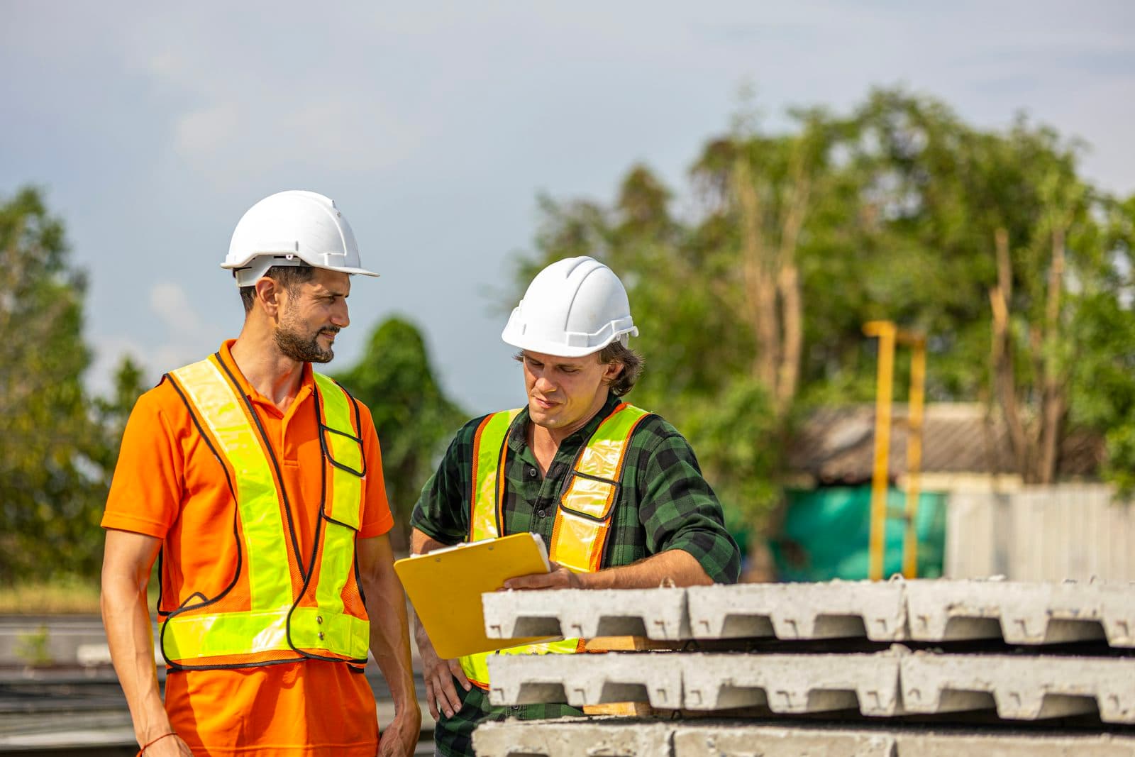 Two construction workers reviewing plans on a clipboard
