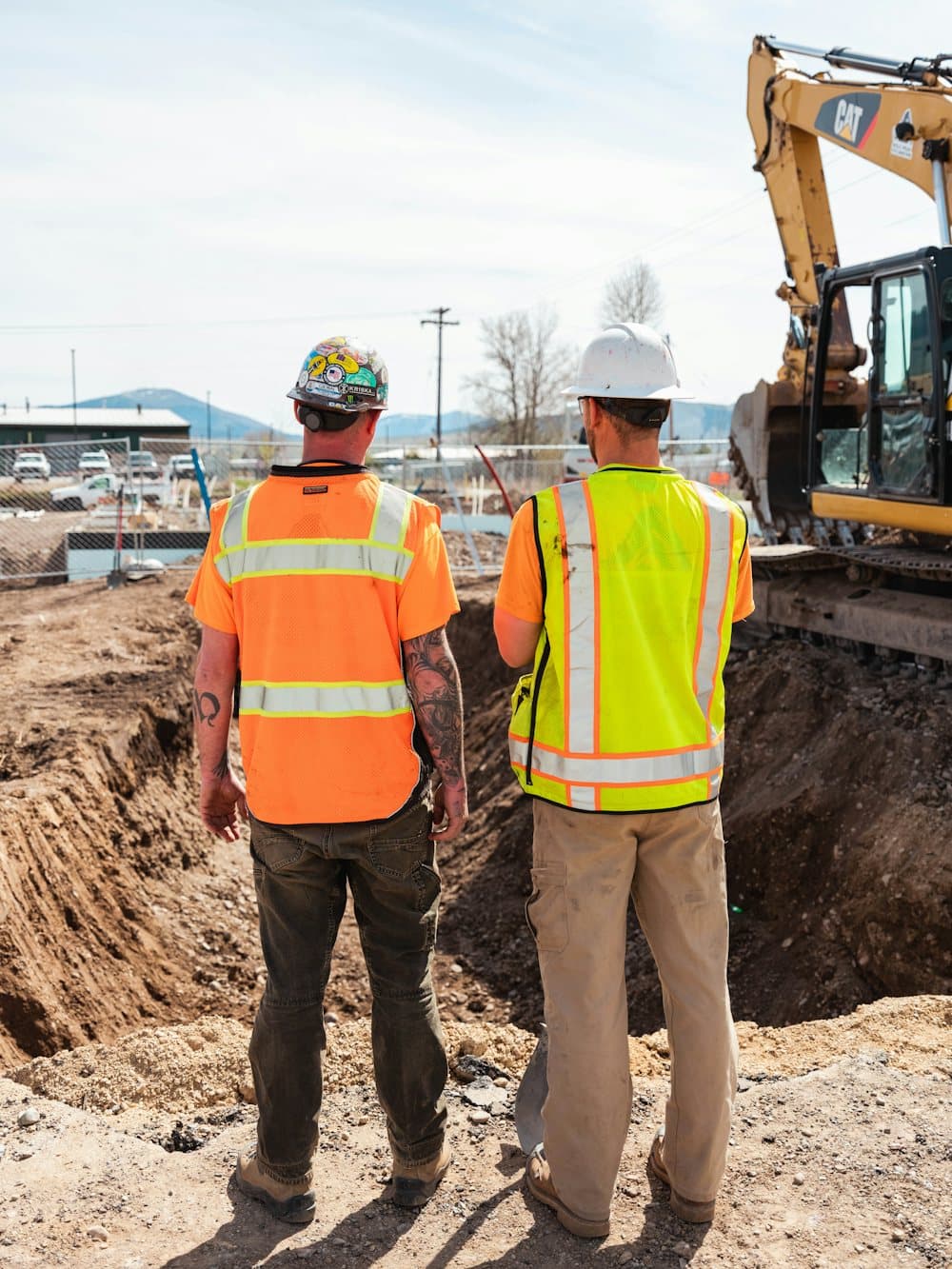 Two workers in hi-vis vests at an excavation site